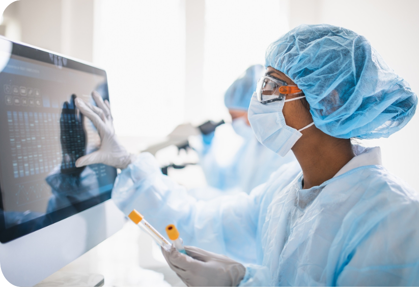 a person in a lab coat and mask using a computer